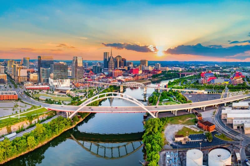 Aerial view of downtown Nashville skyline at sunset with river and arched bridges, showcasing urban development and infrastructure relevant to land surveying services