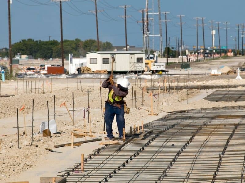Construction staking in progress at a job site with layout stakes and foundation preparation before development