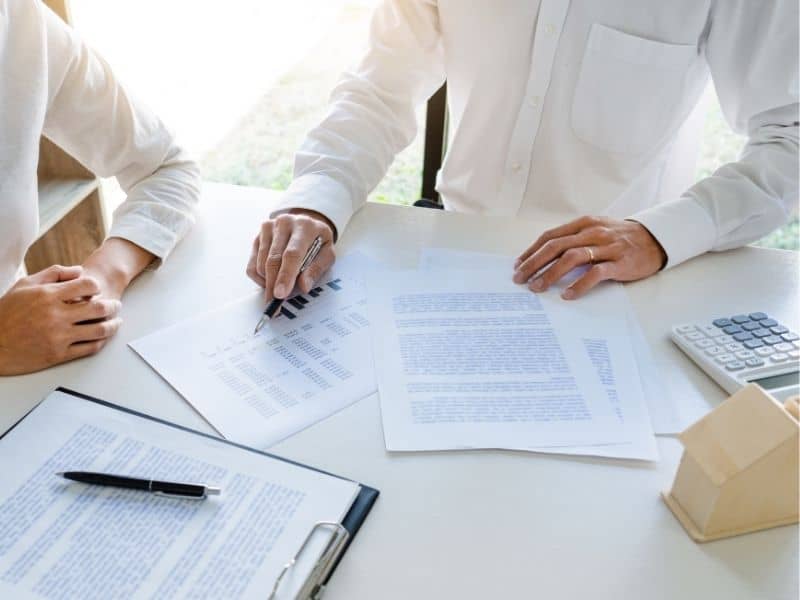 Property owners reviewing legal documents and a title report during a real estate transaction before confirming property boundaries and ownership.